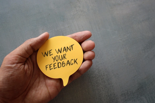 A hand holding a sticker that's asking for feedback